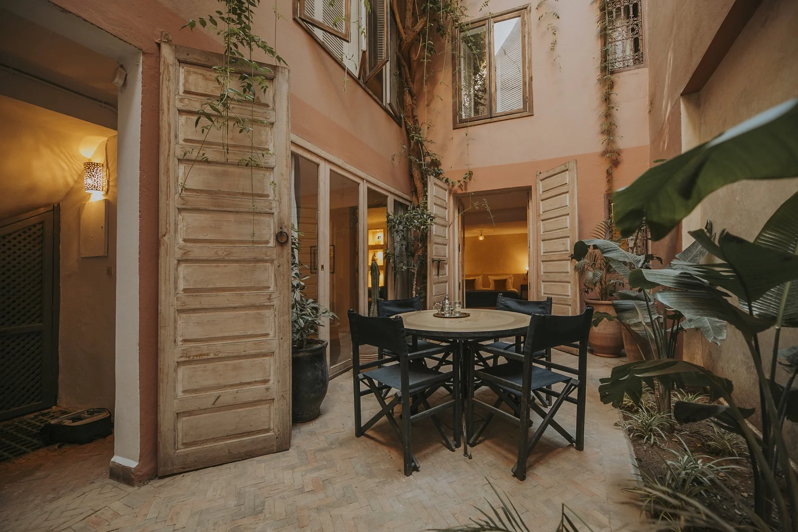 The sunlit patio of Riad Dar Zelda — arcades, greenery and the fountain at the heart of the merchant's house