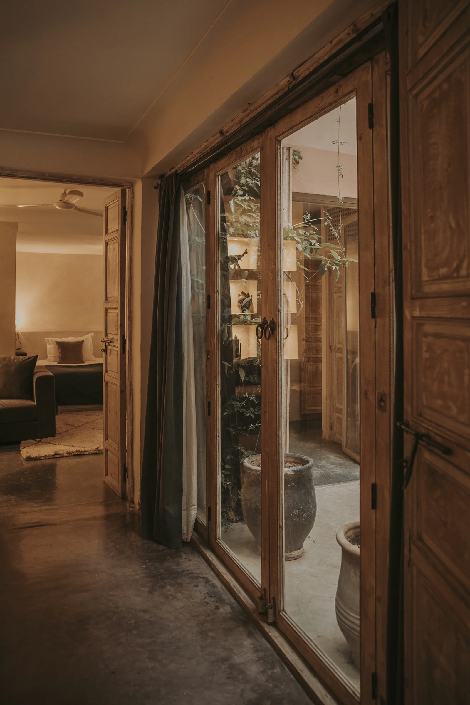 The corridor of Riad Dar Zelda opening onto the sunlit patio, between antiques and forged iron