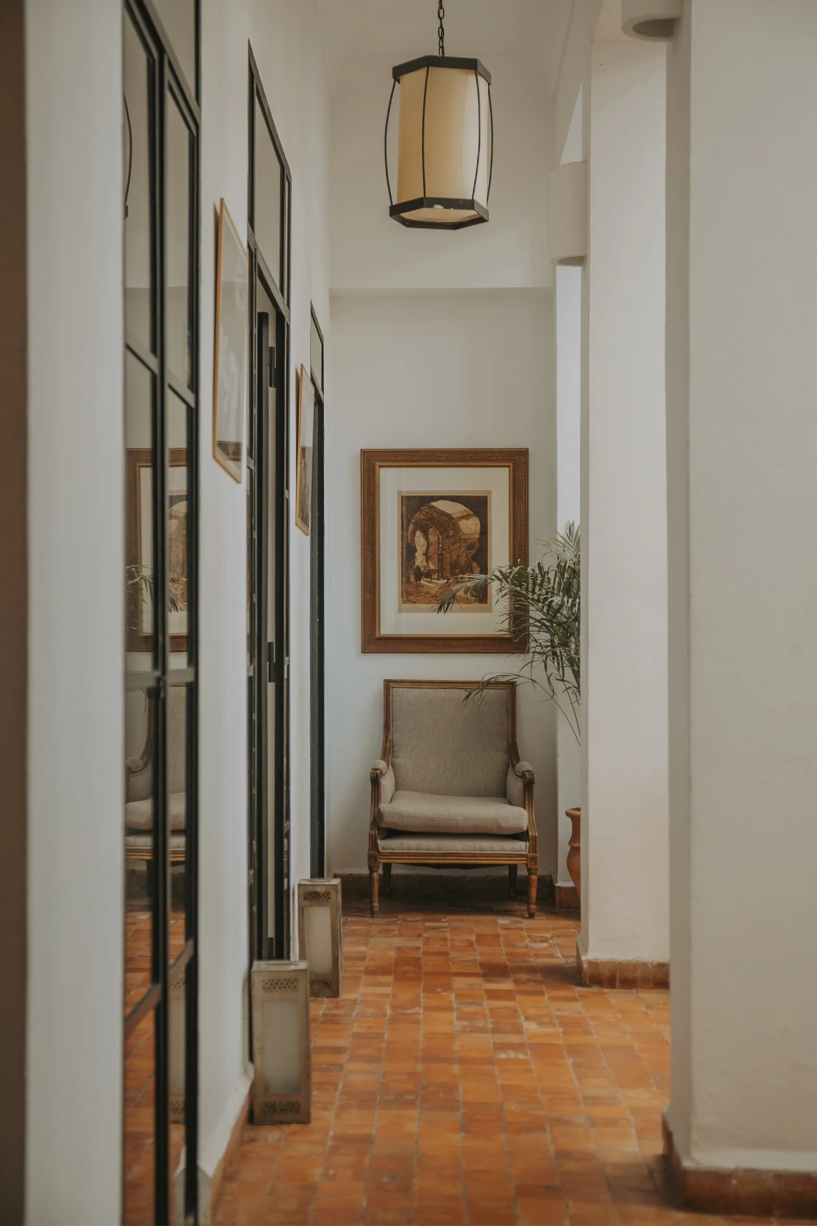 A corridor of Dar Zelda — an antique armchair beneath framed works, the collection along the walls