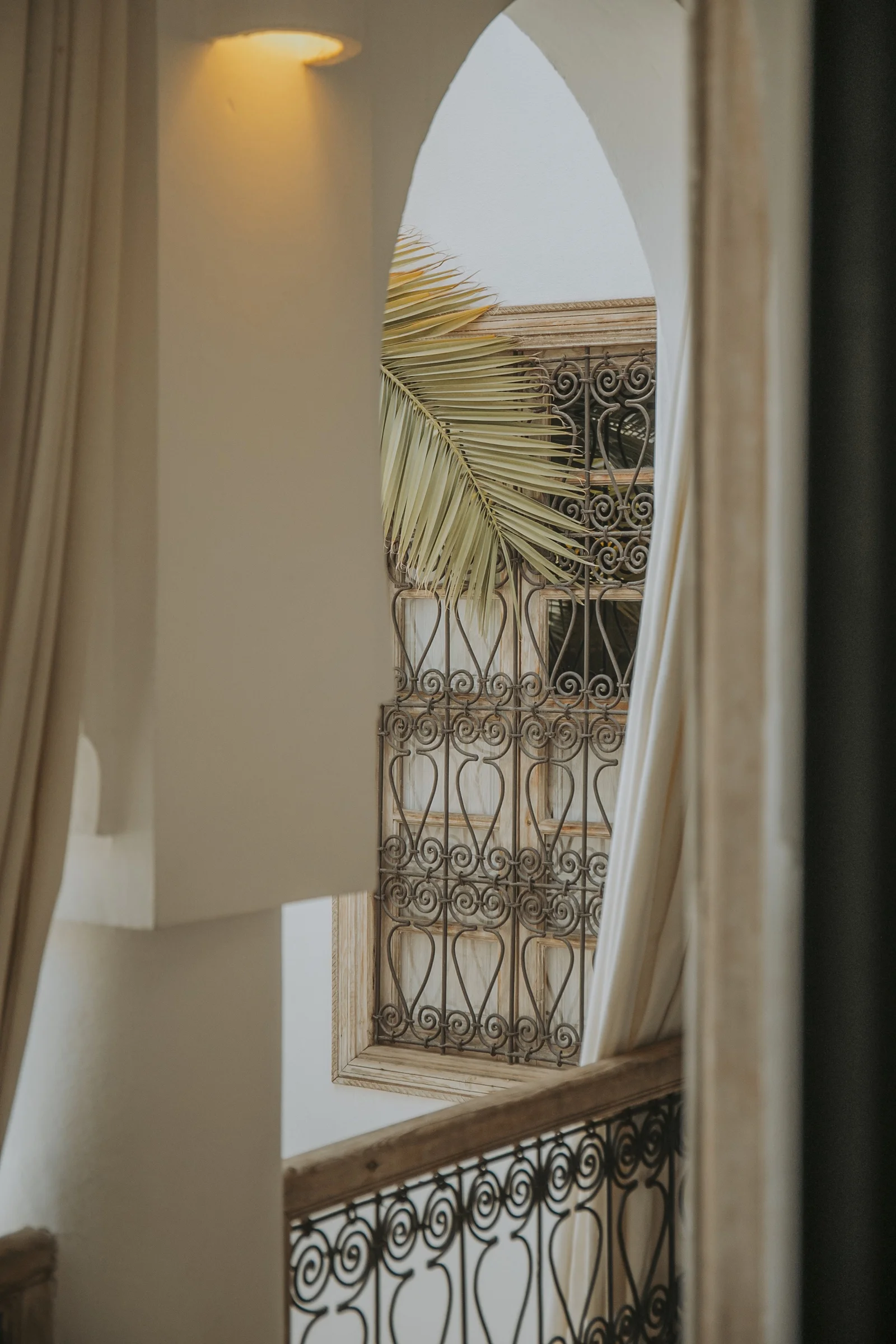 A moucharabieh window of Dar Zelda seen through the arch, a palm frond across it