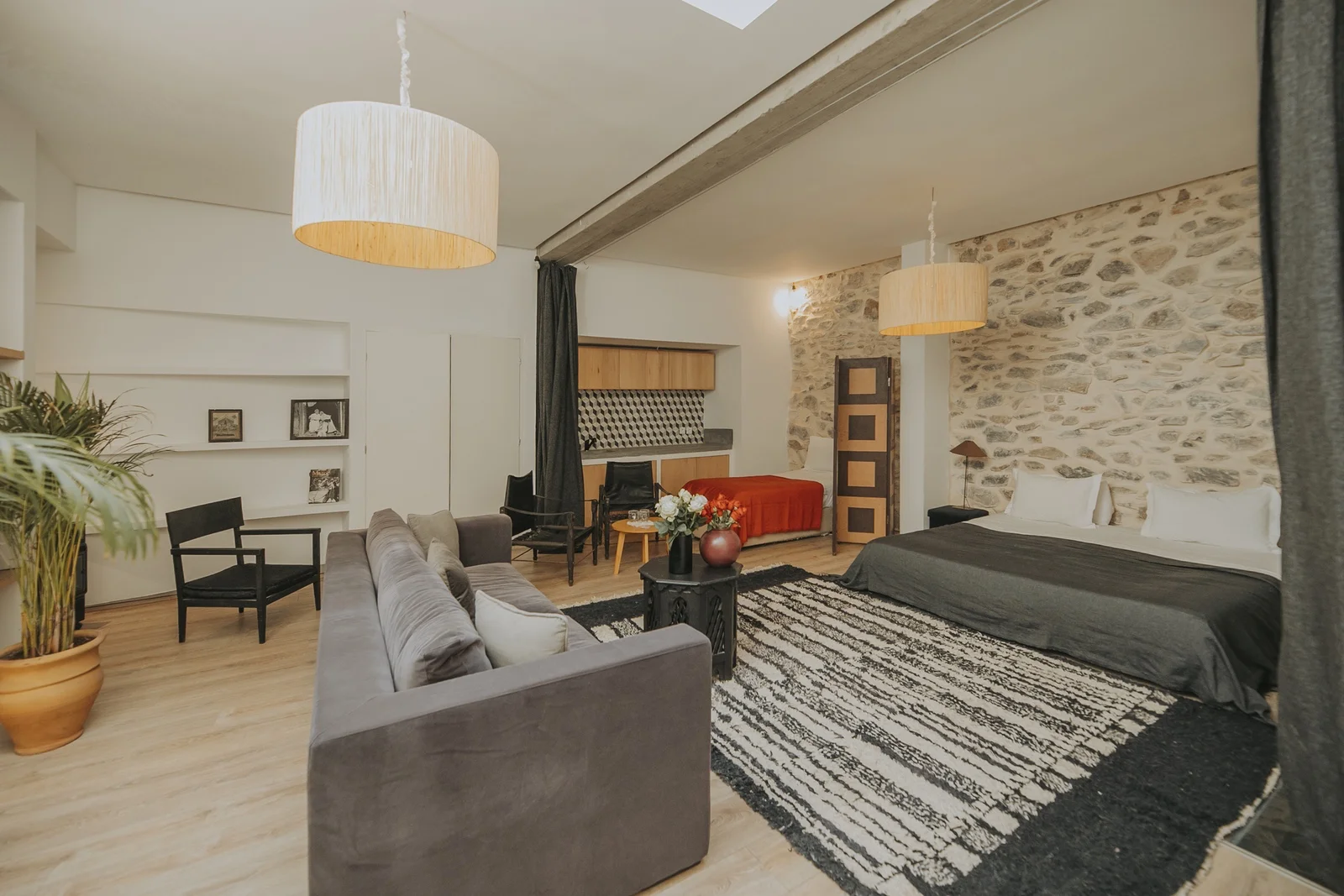 The loft under its beams, a bare stone wall behind the bed