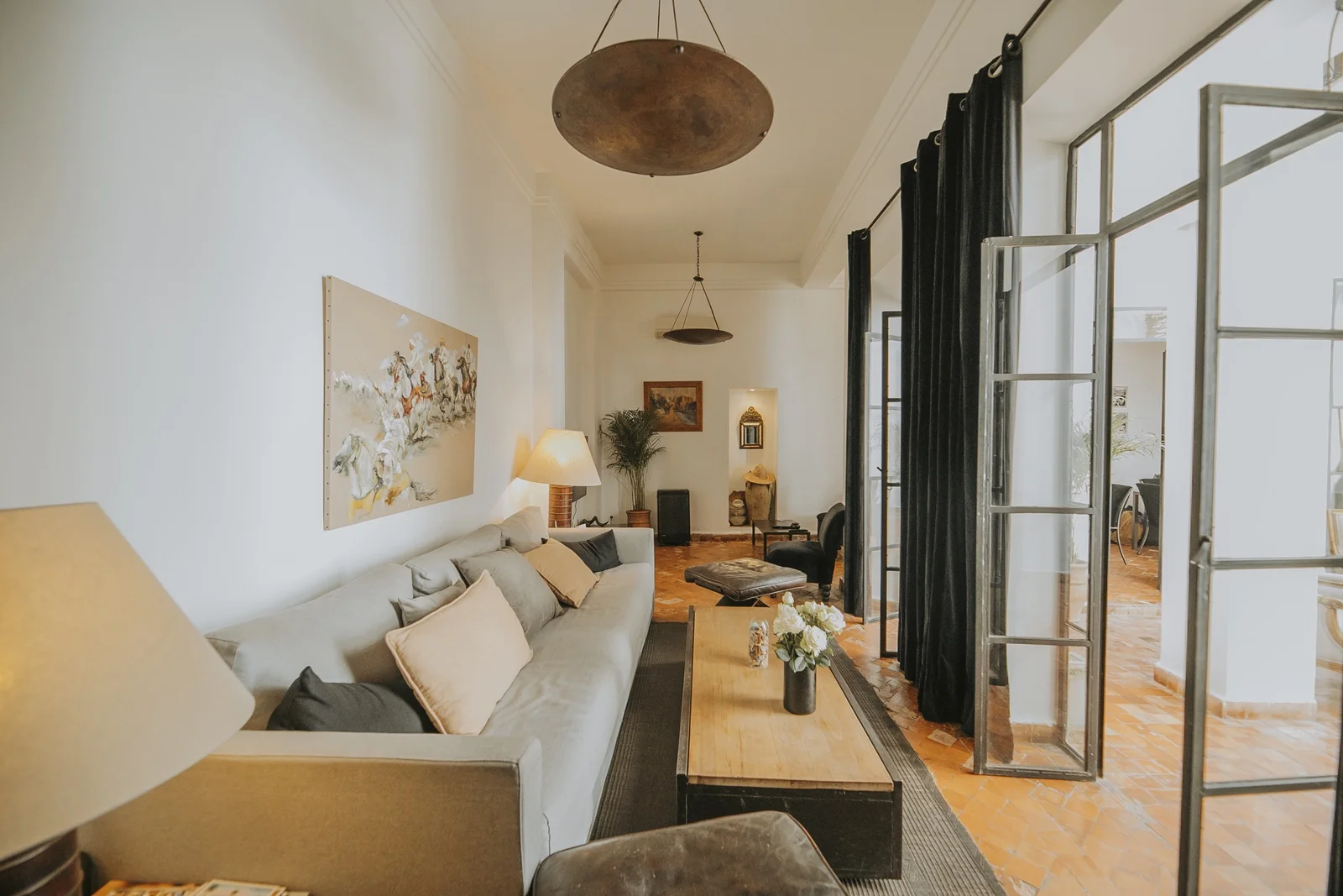 The grand salon of Dar Zelda — linen sofas, the art collection and iron doors onto the patio