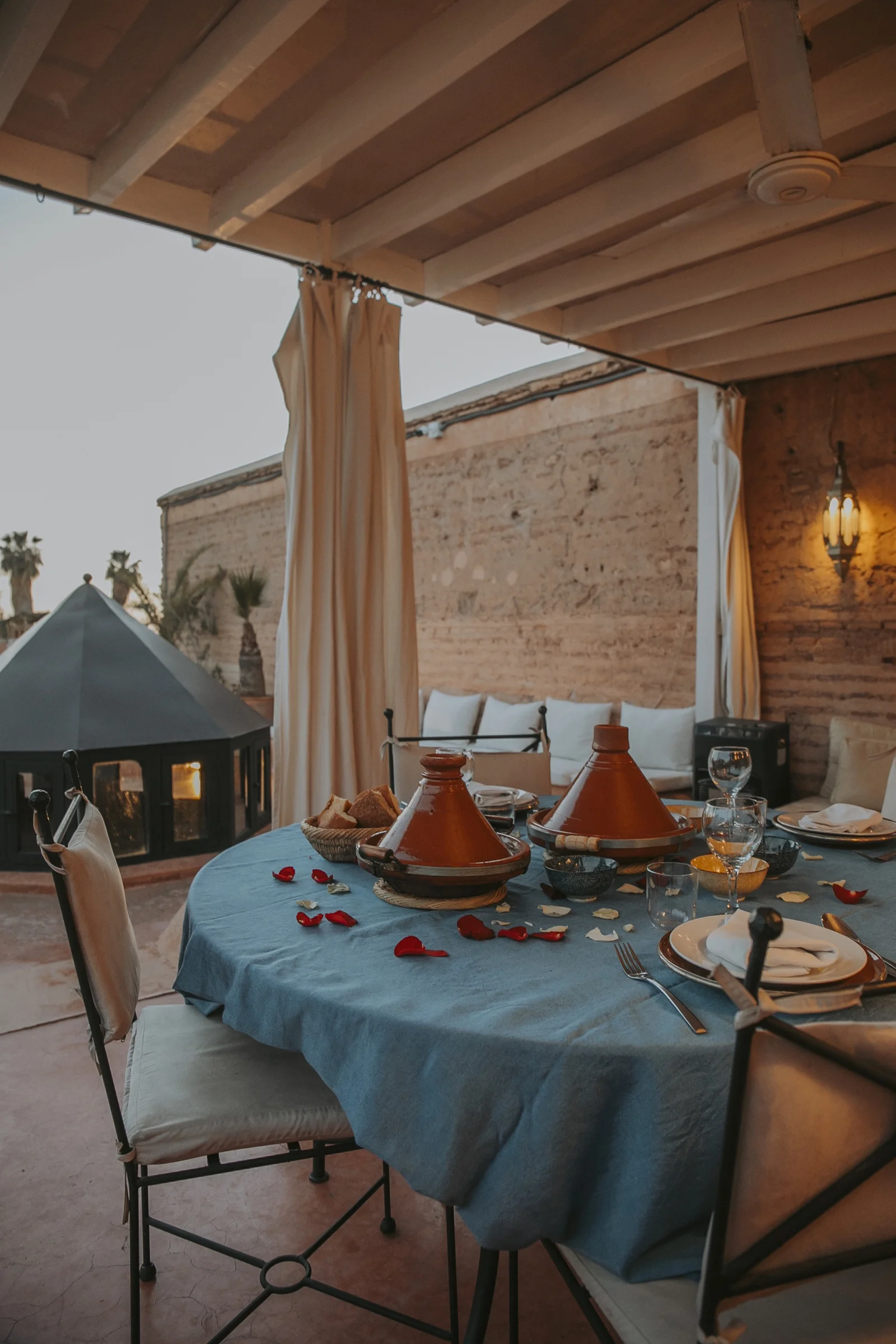 The table d'hôtes on the rooftop terrace of Dar Zelda, tagines and rose petals at nightfall