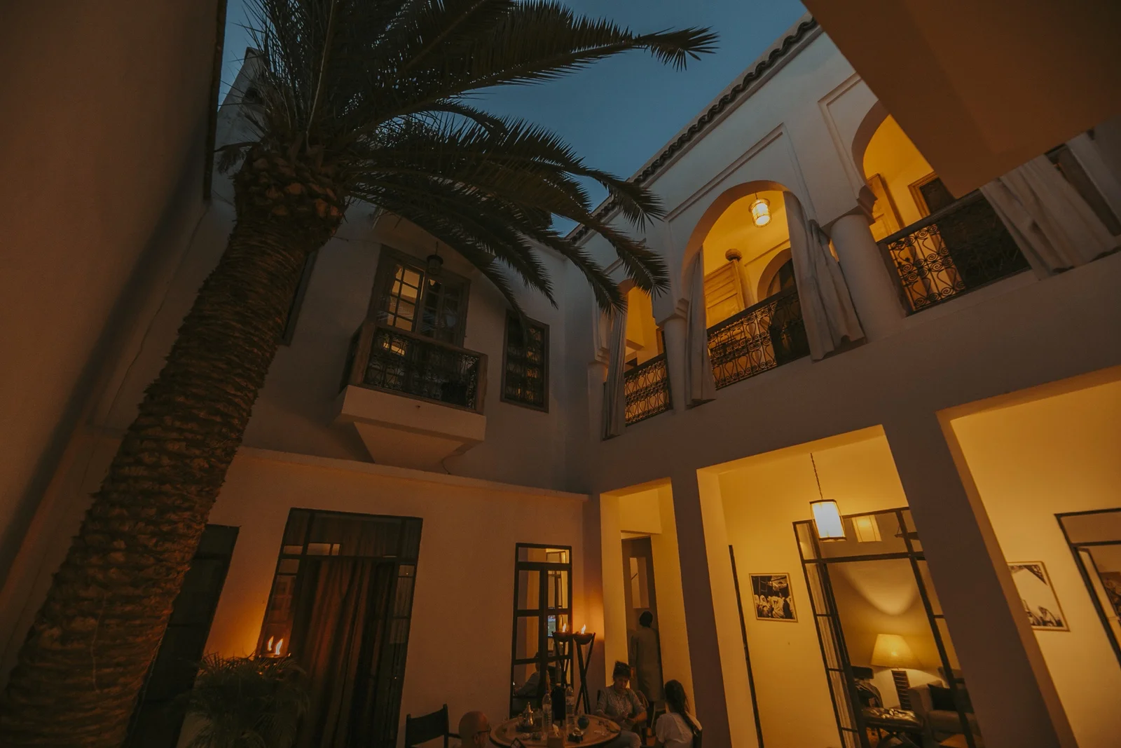 Dinner served in the patio of Dar Zelda at dusk — lanterns lit beneath the arcades and the palm tree